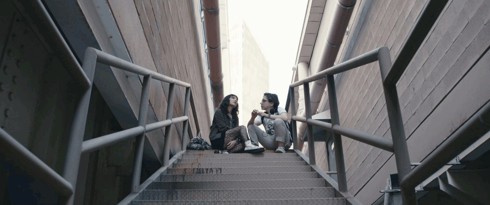 Dos protagonistas de Mi Chica Púrpura conversan sentados en una escalera